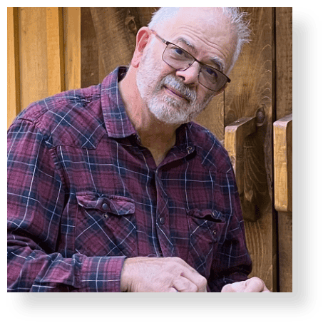 Experienced man in casual attire leaning against wooden background, showcasing confidence and approachability in professional portrait mode.