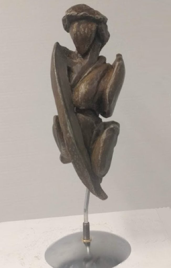 Elegant wooden abstract sculpture of a woman with a hand resting on her face, symbolizing contemplation and grace, mounted on a silver stand, by Richard Comparey.