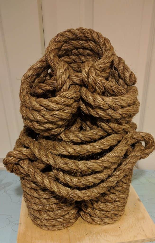 Thick, natural fiber rope coiled in a large bundle, showcasing rugged texture and rustic appearance. Ideal for maritime, decorative, or industrial purposes, emphasizing durability and craftsmanship.