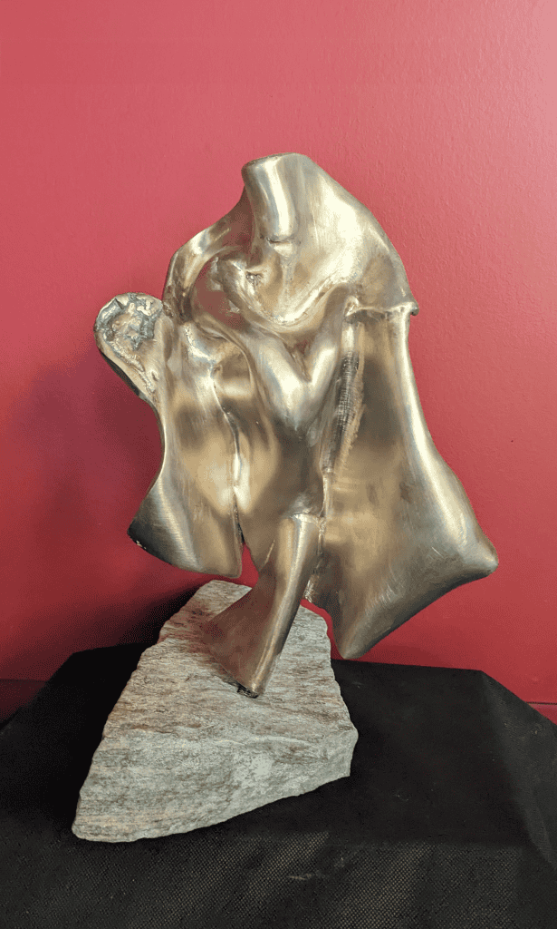 Elegant abstract metal sculpture by Richard Comparey portraying a contemplative human figure, showcasing modern art and artistic craftsmanship, mounted on a textured stone base.
